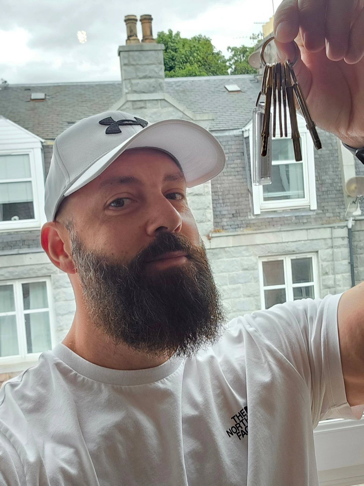 Tom Psyllas holding up a set of keys outside a granite tenement in Aberdeen