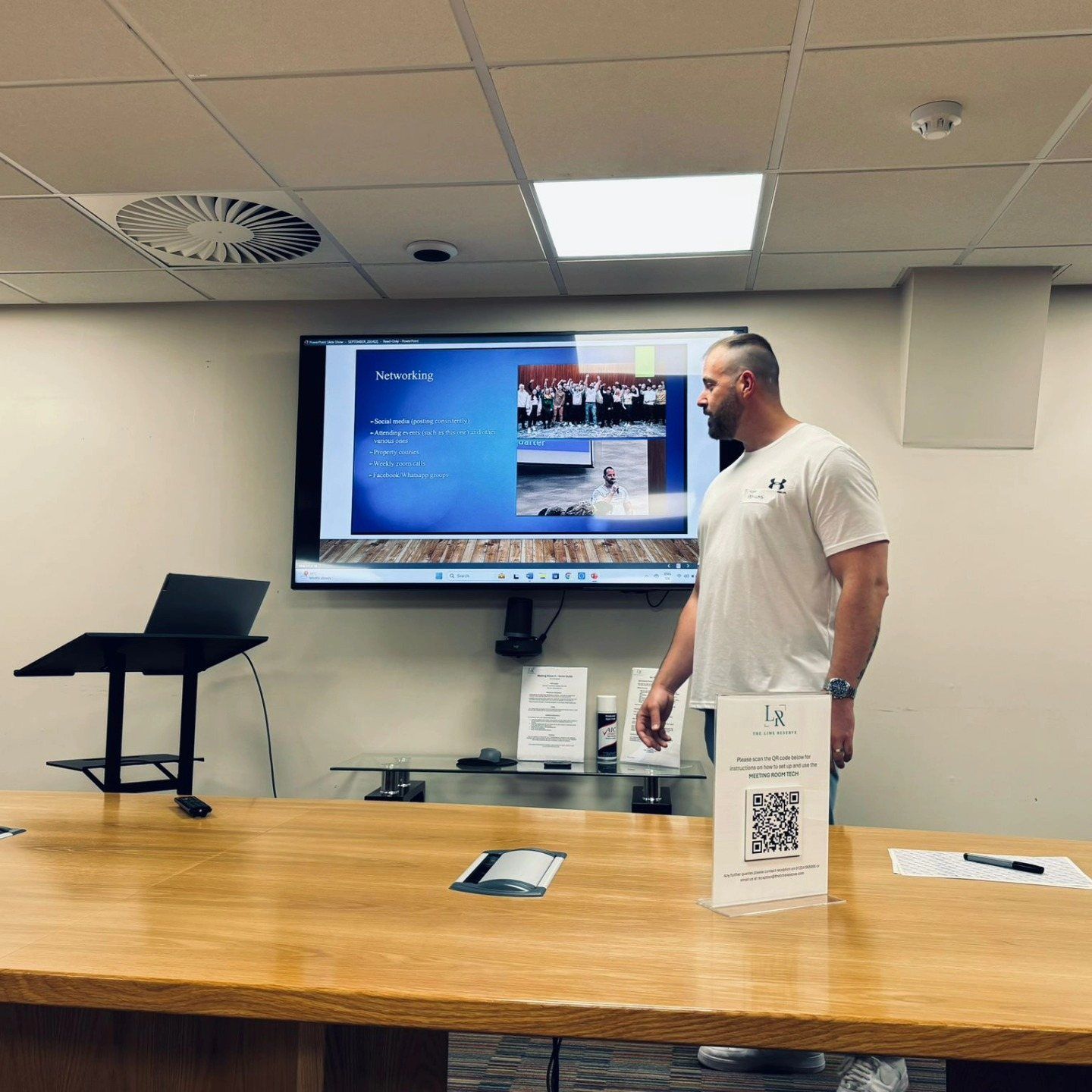 Tom Psyllas standing in a meeting room in front of a presentation screen